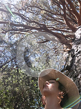 Close up of female with hat leaning on a Scots Pine Pinus Sylvestris, while she meditates bonding with the tree.