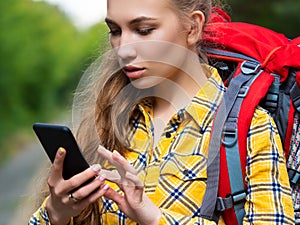 Close up of female hiker looking at her mobile phone. Lost in forest and using GPS app in mobile phone.