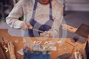 Close Up Of Female Jeweller Working On Ring With File In Studio