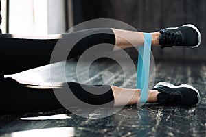 Close-up of a female leg with a sports elastic band for training. Girl fitness trainer doing exercises for legs