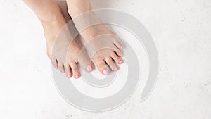 Close up of female legs with a beautiful delicate pink pedicure on a white background. feet care.