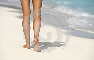Close-up of female legs in the blue water on the tropical beach. Vacation holidays