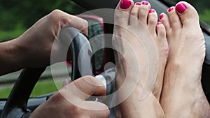 Close-up of female legs with bright nail varnish, pedicure. lie in front of windshield, near steering wheel. it`s