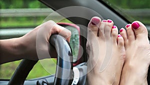 close-up of female legs with bright nail varnish, pedicure. lie in front of windshield, near steering wheel. it& x27;s