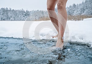 Close up of female legs getting into ice cold water