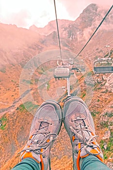 Close-up of female legs in sneakers in mountains on the cable car