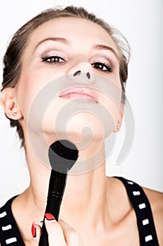 Close-up Female model applying makeup on her face. Beautiful young woman applying foundation on her face with a make up