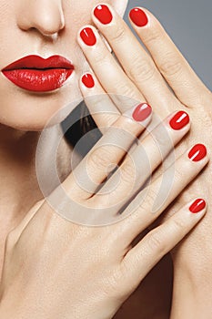 Close-up of female mouth and nails with red manicure and lipstick. photo