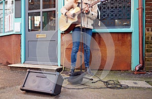 Close Up Of Female Musician Busking Playing Acoustic Guitar Outdoors In Street