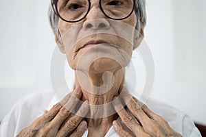 Close up of female neck,asian senior woman thyroid gland control,old elderly was touching the neck,checking thyroid gland with her photo