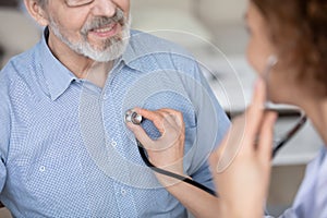 Close up of female nurse check mature patient heartbeat