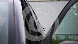 Close up of female opening car door outdoors in the street. Art. Dark car door being opened by a woman on grey metal