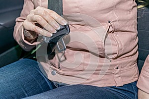 Close-up of a female passenger`s hands trying to fasten their seat belt in a modern car