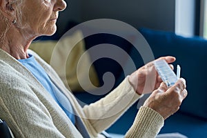 Close-up of female pensioner in casualwear holding small plastic pill-box