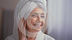 Close up female portrait happy 50s middle-aged lady 60s mature woman touching facial skin looking at camera with smile