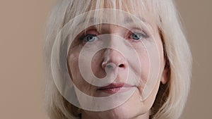 Close up female portrait in studio indoor head face wrinkled calm serious granny mature 60s woman middle-aged blonde