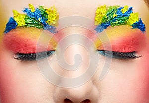 Close-up female portrait with unusual face art make-up with paint on brows. Eyes closed