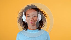 Close-up, female portrait, Young smiling woman in big white wireless headphones looks at camera. Isolated on a bright