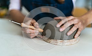 Close up female potter modeling clay bowl in workshop