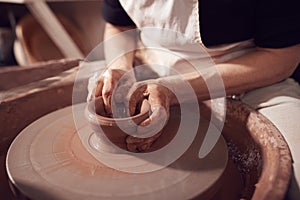 Close Up Of Female Potter Shaping Clay For Pot On Pottery Wheel In Ceramics Studio