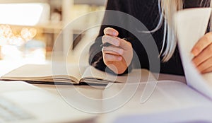 Close-up of female reading books on desk in library