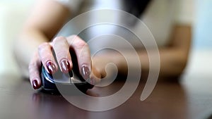 Close up of female's hand holding computer mouse, young business woman using computer in her office