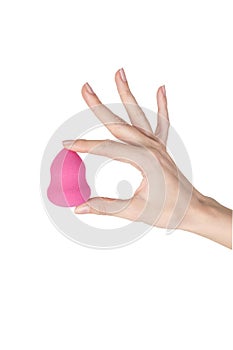 Close up female`s hand holding a pink beauty sponge.