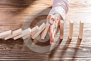 Female Hand Stopping The Domino From Falling photo