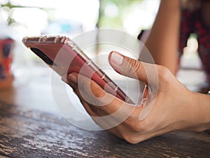 Close-up female's hand using smartphone at a outdoor pink case