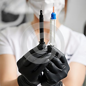 Dentist holding two syringes for gingival protection and teeth bleaching. photo