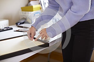 Close Up Of Female Teenage Artist Framing Picture In Studio