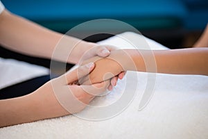 Close-up of female therapist holding hands while examining on white towel