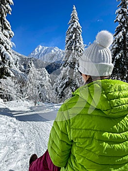 CLOSE UP: Female tourist looks at children before sledding down a forest trail.