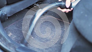 Close-up of female using vacuum cleaner in her car. Car interior cleaning. Woman vacuuming seats. Dust and dirt removal