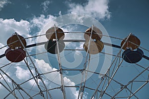 Close-up of Ferris wheel booths with a cloudy blue sky in the background