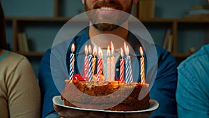 Close up festive cake with burning candles happy bearded unrecognizable birthday man smiling make wish celebrate event