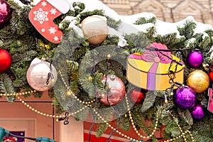 close up of festive christmas city decoration. fure tree brunch covered with snow decorated with baubles and garlands