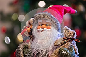 Close up of a festive Father Christmas Doll with Christmas tree and lights