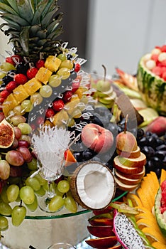 Close up of festive table different fresh fruits with pineapple, coconut, grapes, berries, watermelon, apples, pomegranate.