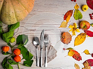 festive thanksgiving autumn cutlery setting and arrangement of colorful fall leaves, red berries, pumpkin