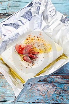 Close up of feta-cheese with herbs and tomato slice in foil