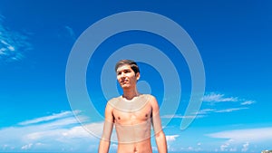 Close-up figure of a young tanned guy on the beach against the blue sky