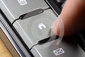 Close-up of a finger poised to press a keyboard button with a home icon, online internet real estate activities purchasing, buying