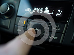 Close up finger press the button to turn on air condition in car