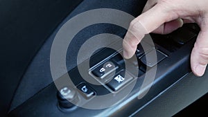 Close-up of finger pressing button controlling and adjustments window in car. Technology and transportation concepts.