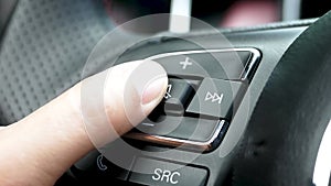 Close up of finger pressing the button to mute or unmute on the steering wheel when driving.