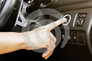 Close up of finger pressing the start/stop engine button at a car