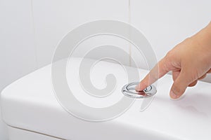 Close up of finger pushing a flush toilet button for cleaning. -
