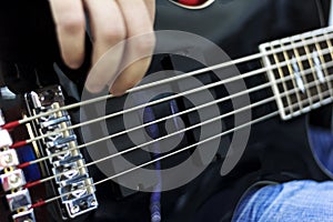 Close up on the fingers of musician playing bass guitar on the stage