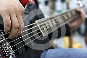 Close up on the fingers of musician playing bass guitar on the stage